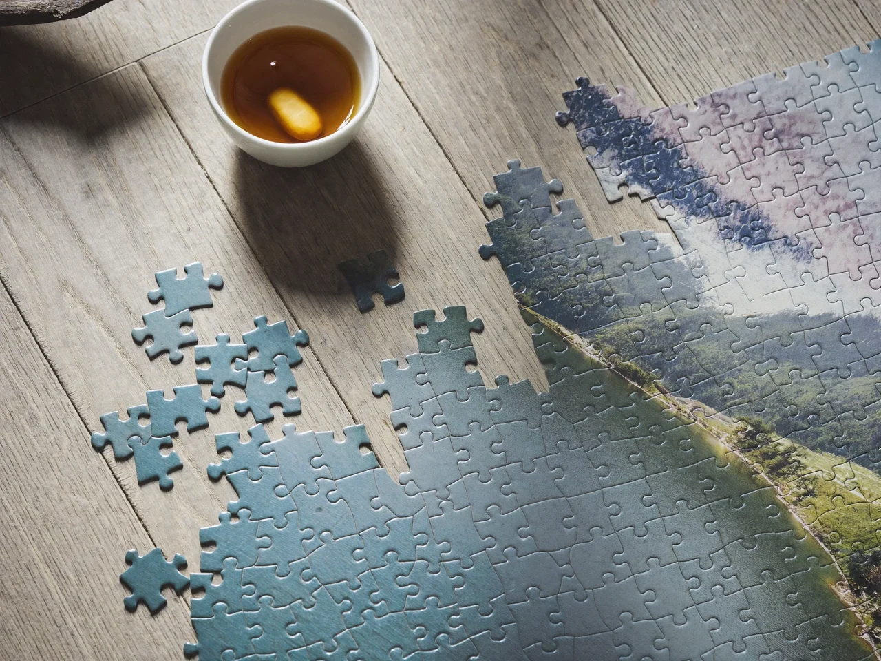Fertig gelegtes 1000-Teile-Puzzle mit Bergsee-Motiv auf hellem Eichentisch