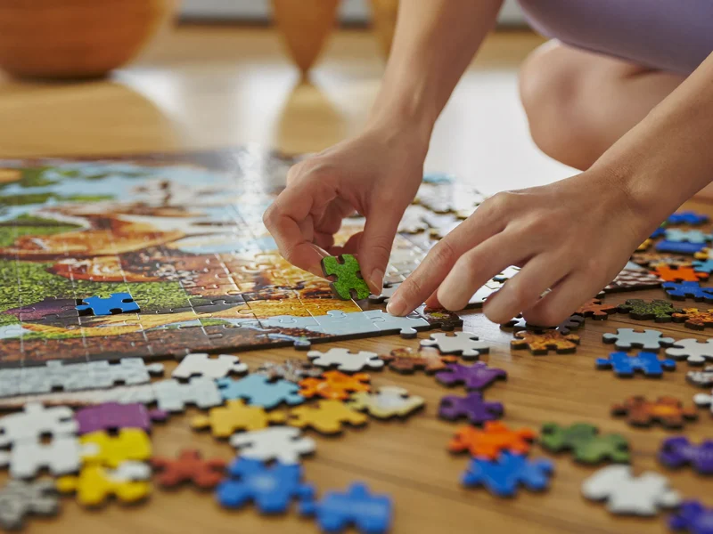 Kinderhände legen ein grosses Tierpuzzle auf dem Spielzimmerboden