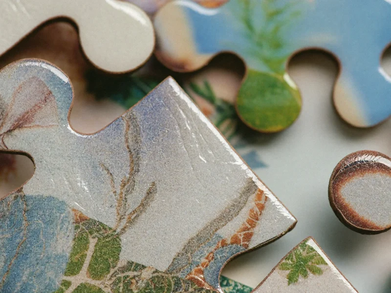 Makroaufnahme ineinandergreifender Puzzleteile mit Kartonstruktur und glänzender Druckoberfläche